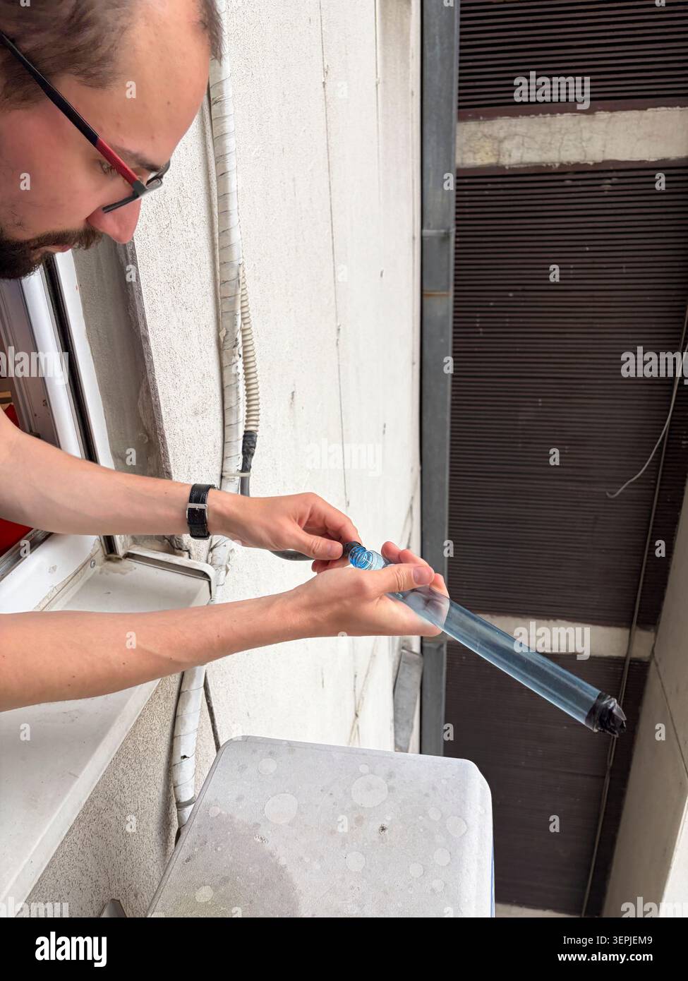 Uomo che prepara una prolunga di drenaggio trasparente per la manutenzione del condizionatore d'aria Foto Stock