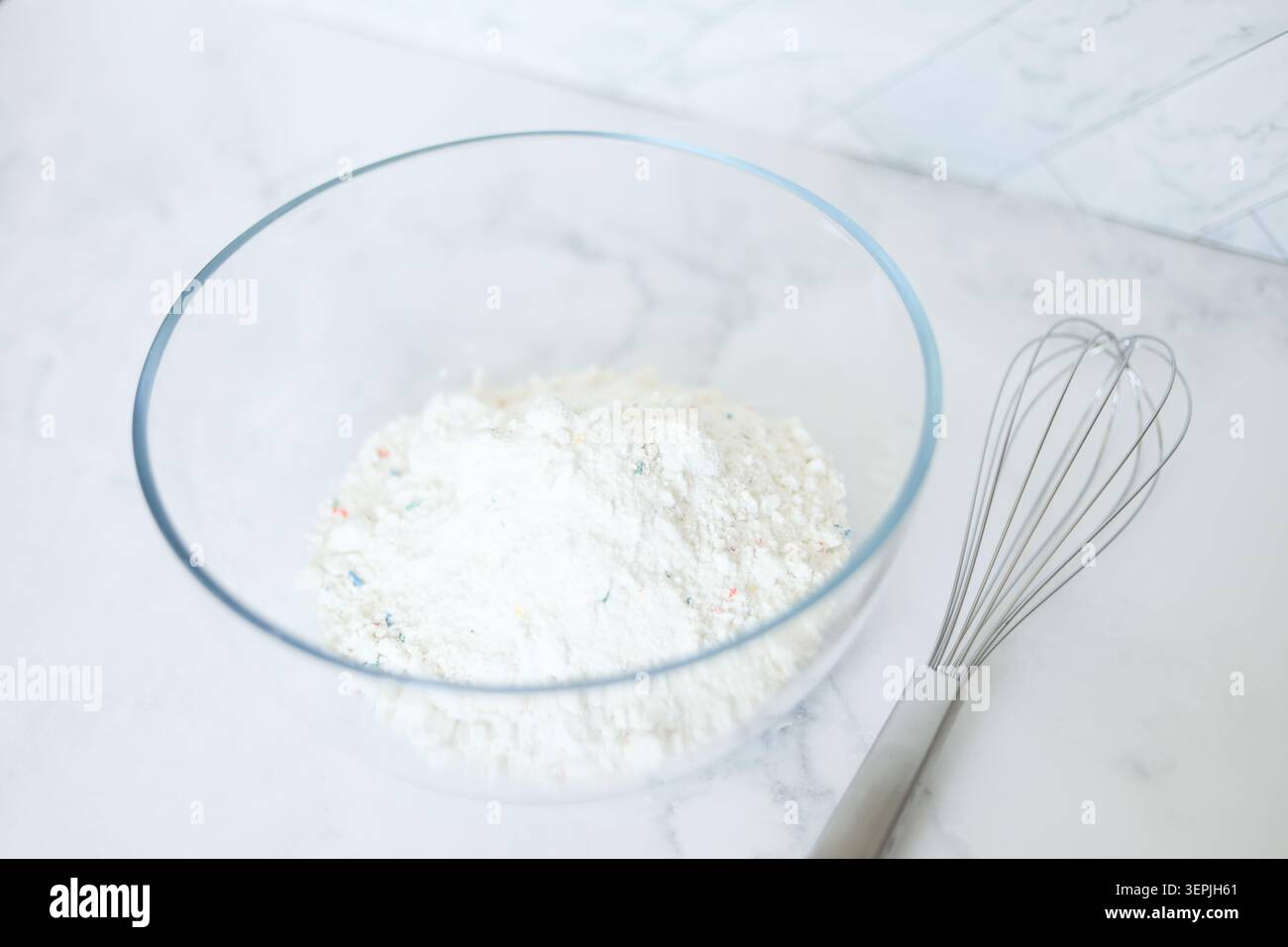 Mescolare la torta Funfetti in un recipiente di vetro con la frusta Foto Stock