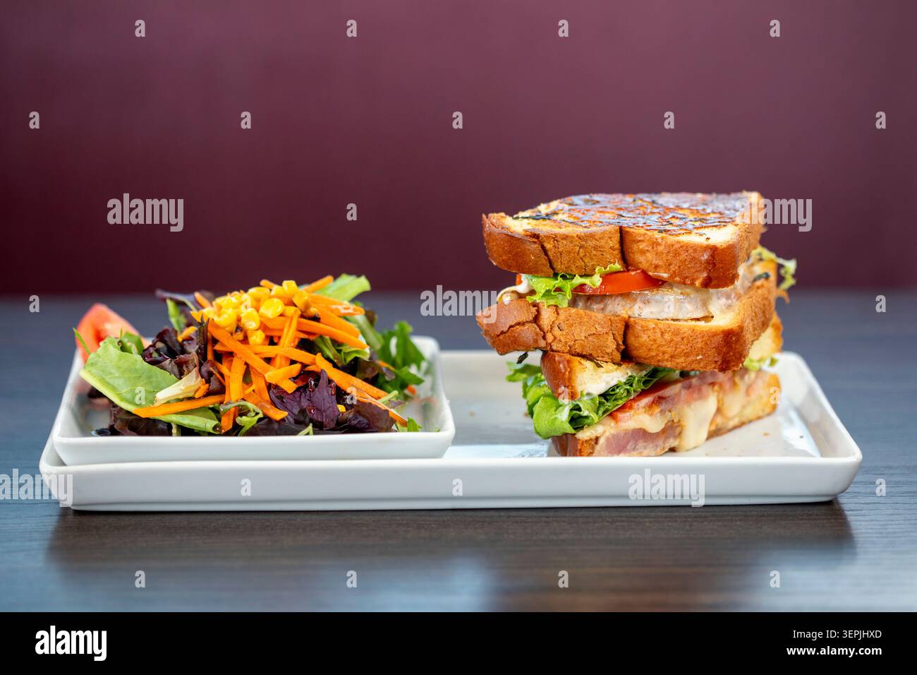 Club sandwich impilato con un contorno di insalata fresca Foto Stock