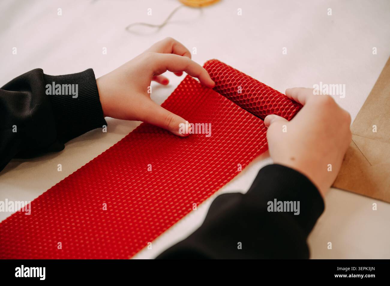 Telo a mano in cera d'api rossa per bambini, un'accogliente lavorazione artigianale fai da te all'interno Foto Stock