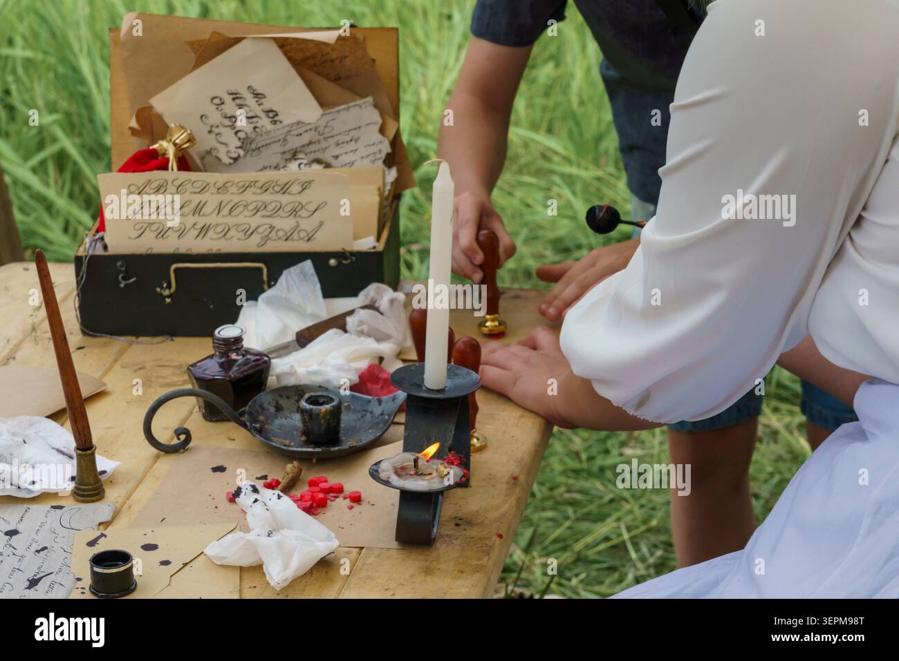 Mosca, Russia - 12 giugno 2025: Rievocazione storica del festival del 1812 con strumenti calligrafici, sigilli di cera e pergamena su un tavolo di legno surrou Foto Stock