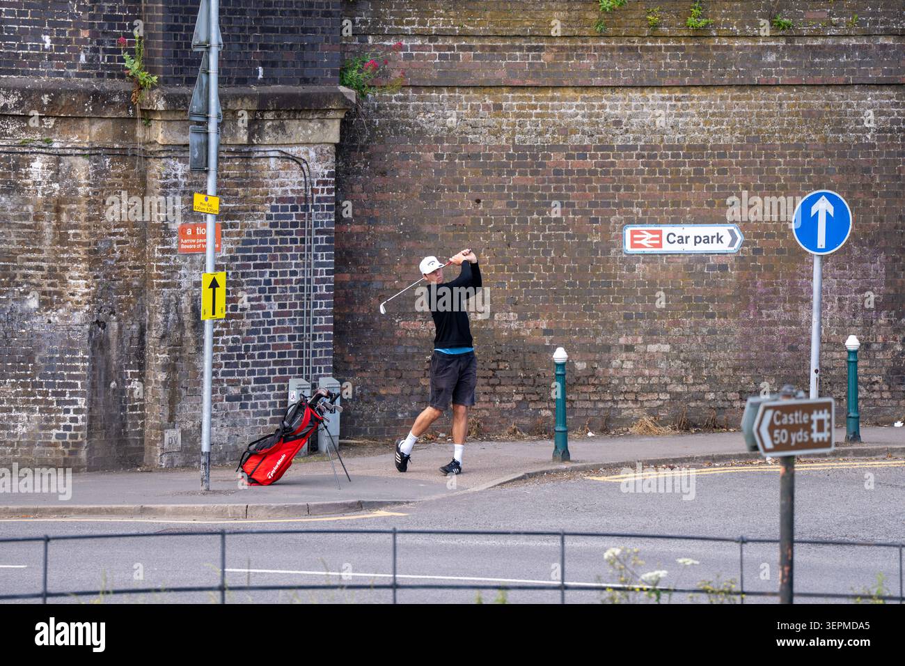 Giovane che pratica il golf swing all'angolo della strada Foto Stock