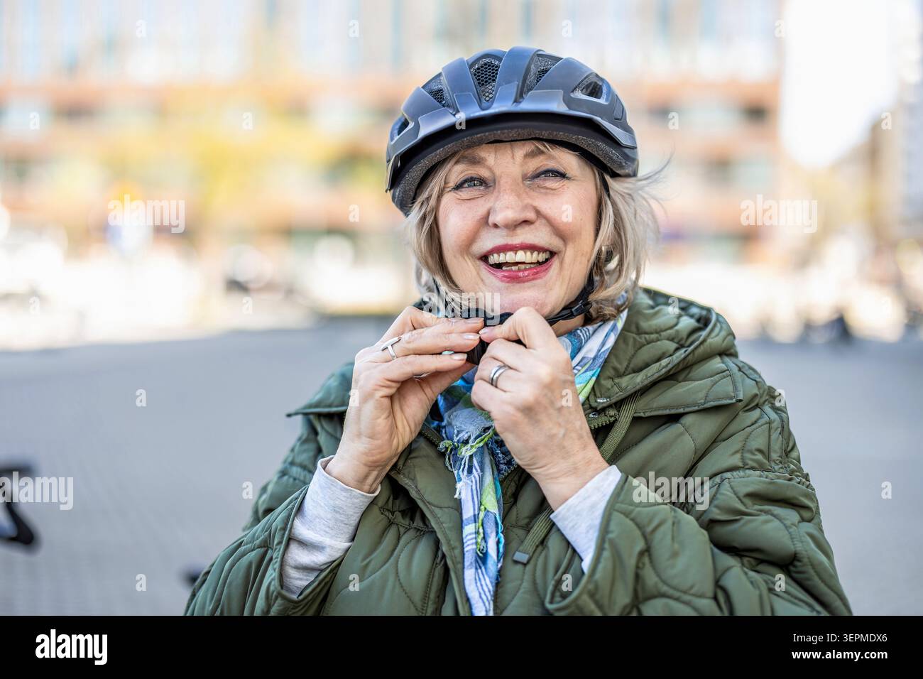 Donna anziana che adatta il casco da bicicletta all'aperto Foto Stock
