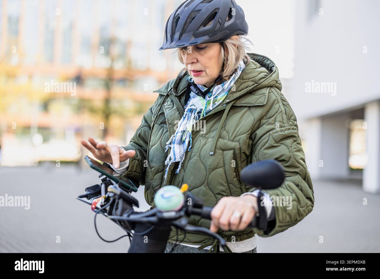 Ciclista anziano che prepara una mappa sul suo telefono prima di andare in bicicletta in città Foto Stock