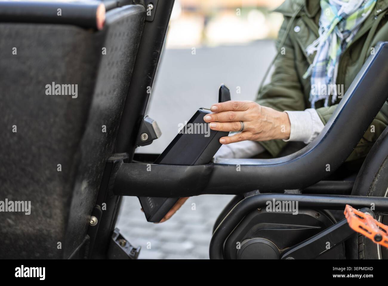 Donna matura che cambia la batteria su una bicicletta elettrica Foto Stock