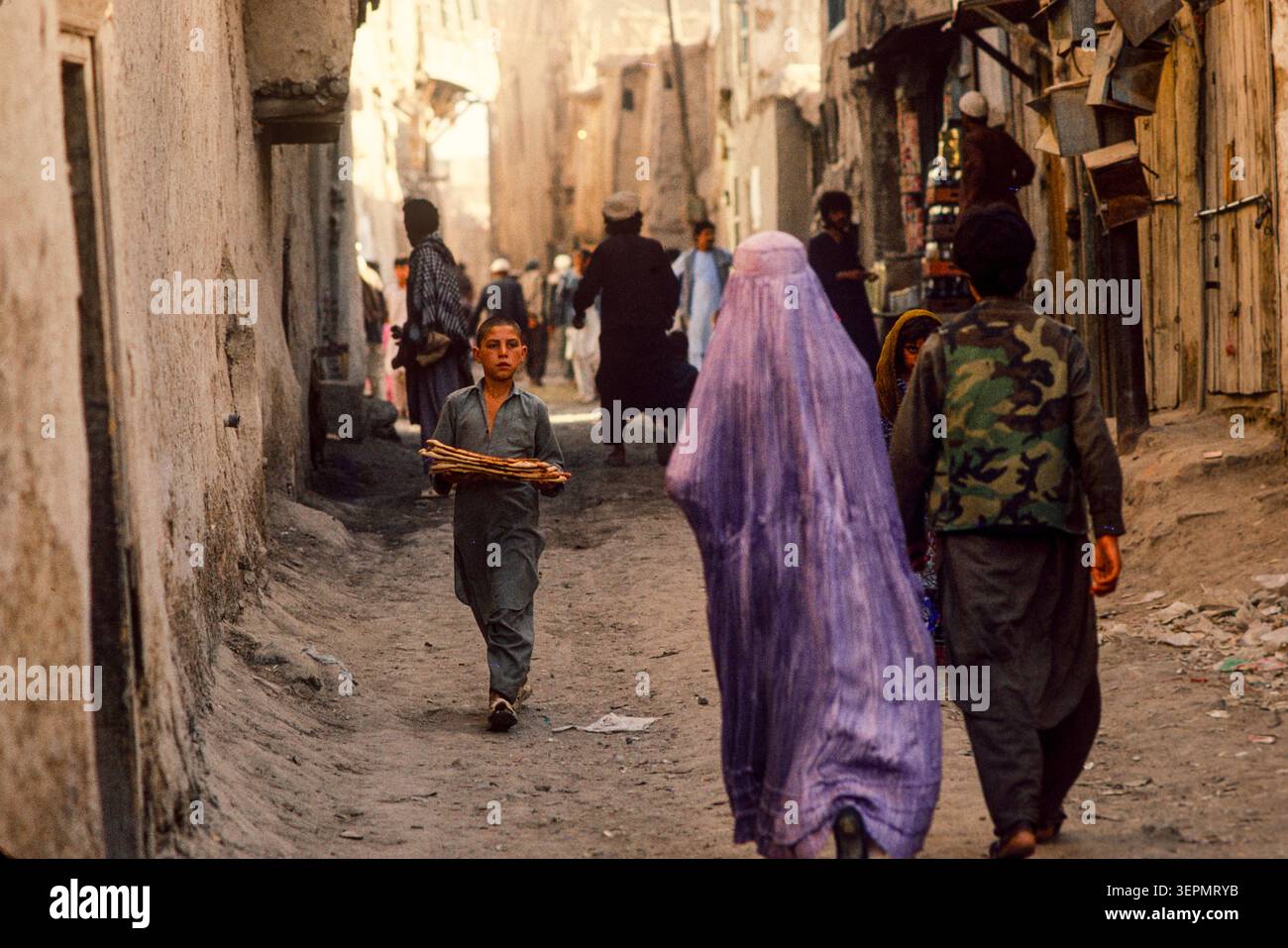 Persone che portano a casa il tradizionale pane naan nelle strade secondarie di Kabul, Afghanistan, agosto 1992 Foto Stock