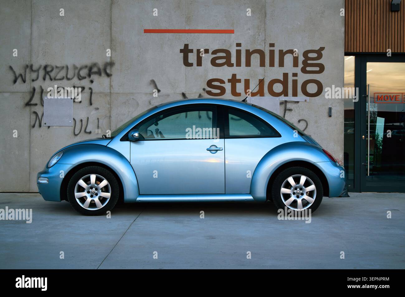 Blue Volkswagen Beetle Car parcheggiata all'esterno dello studio di formazione contro il muro di cemento con Graffiti Foto Stock