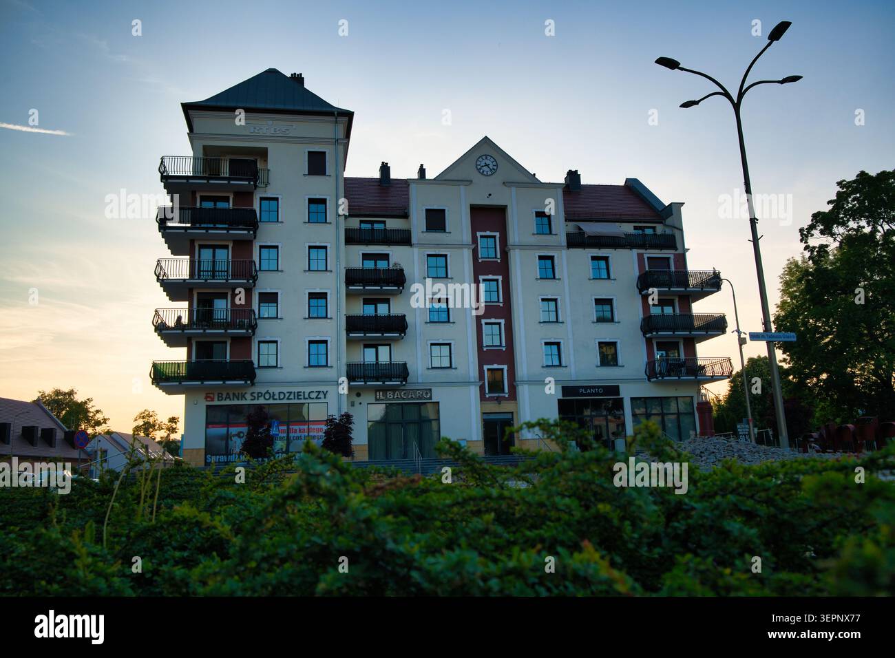Edificio di appartamenti residenziali con filiale di banca e balconi al tramonto - città di Lubin. Foto Stock