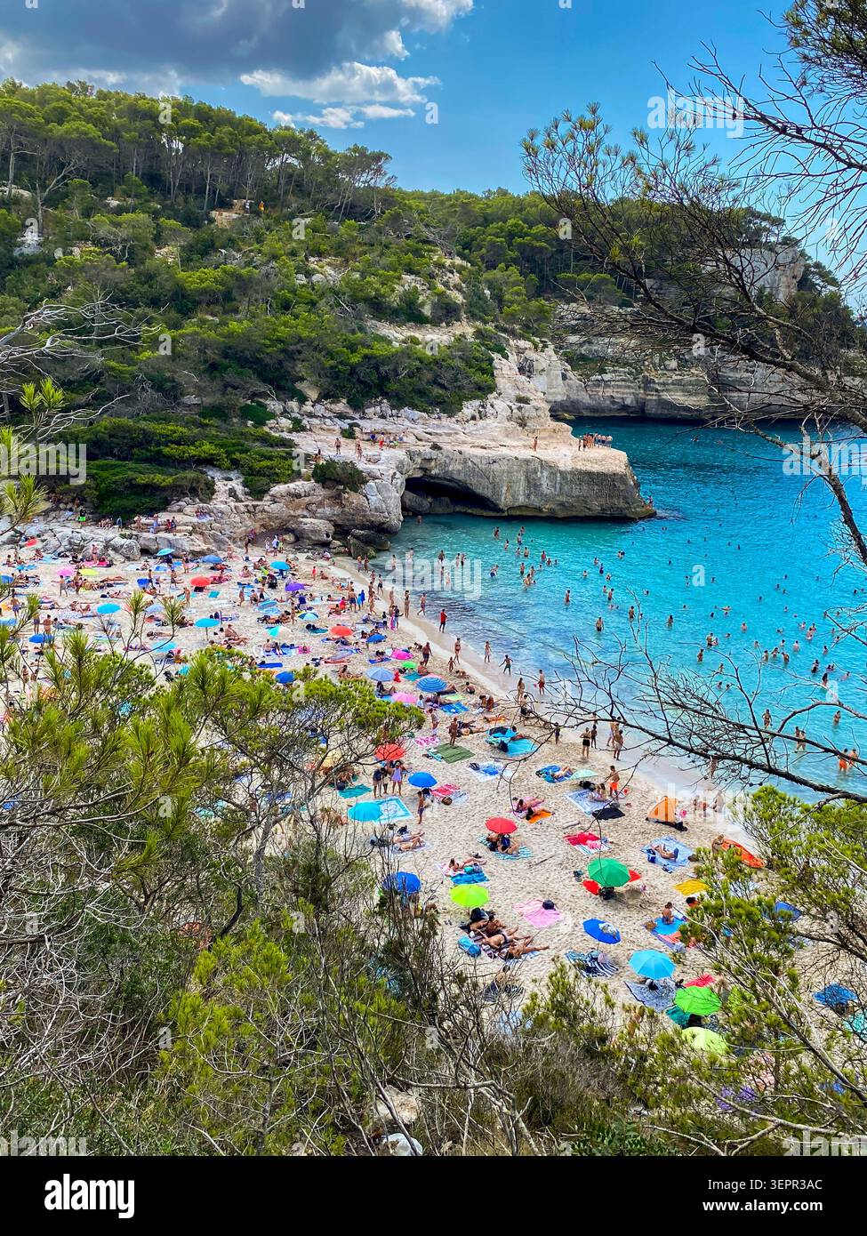 Vista dall'alto della spiaggia di Cala Mitjana a Minorca, Isole Baleari, Spagna. Bellissima baia vergine con sabbia bianca fine, affollata di turisti, cristallo c Foto Stock
