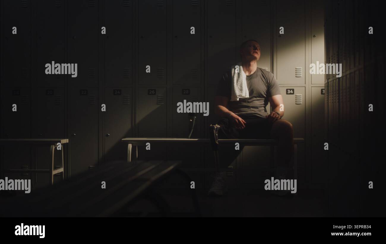 Modern Para Athlete si piega indietro in Quiet Recovery dopo un intenso allenamento, riposando nello spogliatoio. Tecnologia protesica, resilienza, autentica rappresentazione della disabilità nello stile di vita attivo e nello sport. Foto Stock