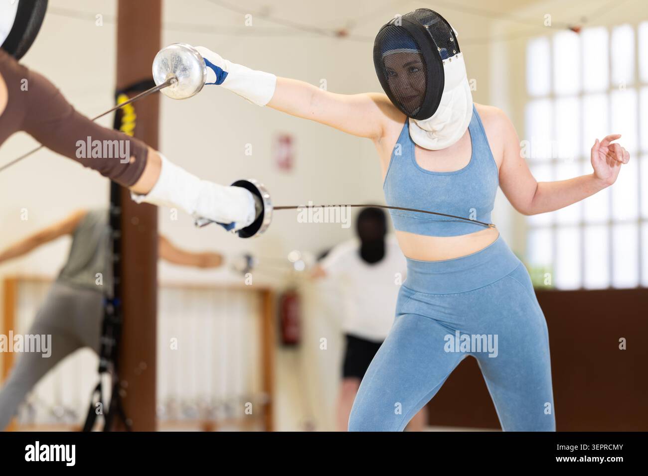 Un gruppo di recinti si allena in duelli e fa uscire i colpi sui cuscini in palestra Foto Stock