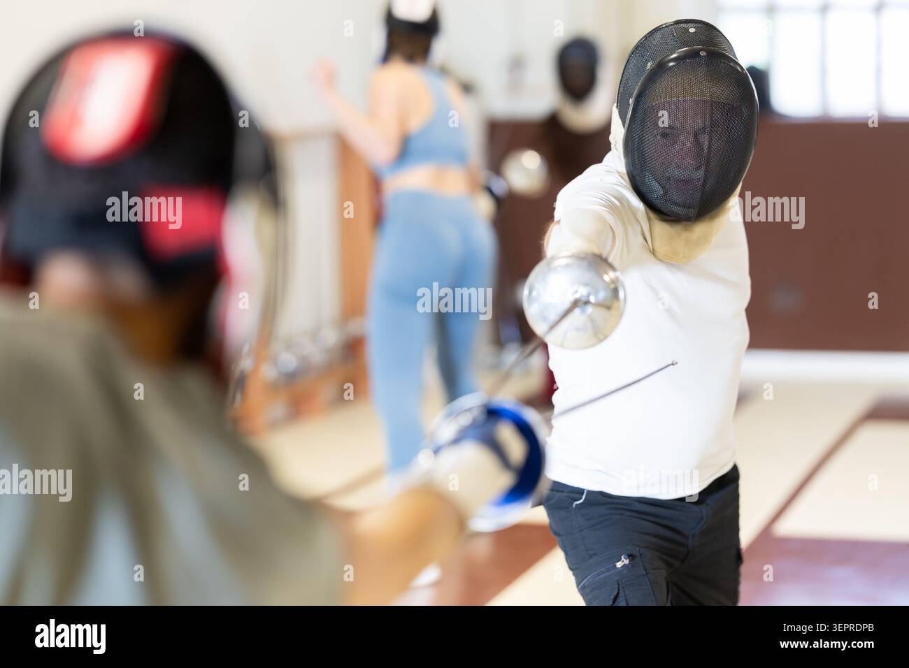 Un gruppo di recinti si allena in duelli e fa uscire i colpi sui cuscini in palestra Foto Stock