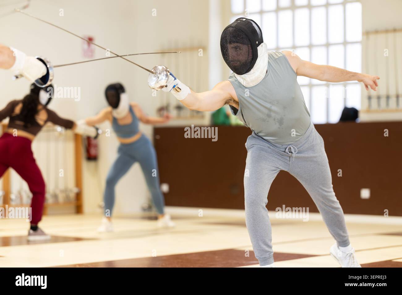 Un gruppo di recinti si allena in duelli e fa uscire i colpi sui cuscini in palestra Foto Stock
