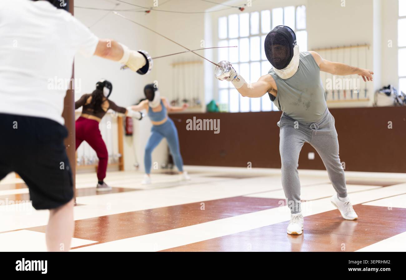 Un gruppo di recinti si allena in duelli e fa uscire i colpi sui cuscini in palestra Foto Stock