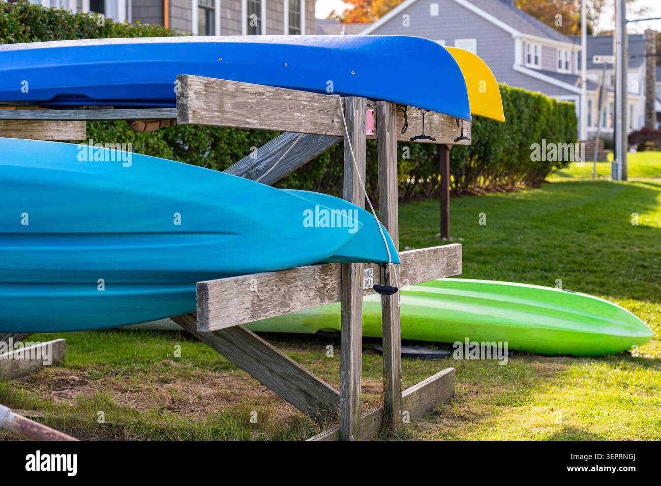 Kayak luminosi e colorati verdi, blu e gialli su un portapattini in riva alla spiaggia della costa del Connecticut. Una scena tipica della Nuova Inghilterra. Foto Stock