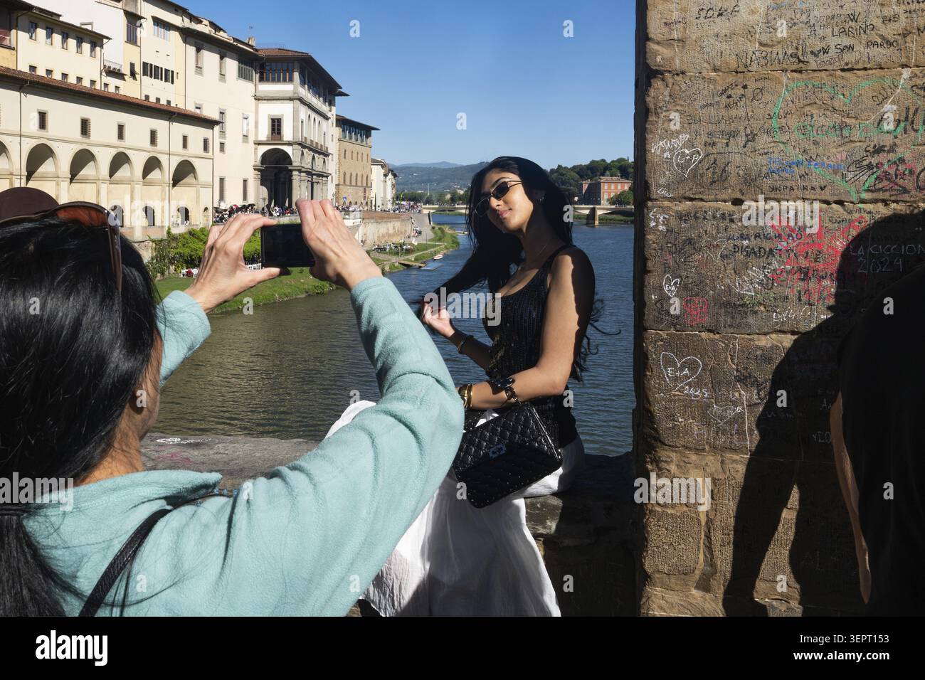 Il turista scatta foto di una giovane donna che indossa occhiali da sole su Ponte Vecchio, Arno, città vecchia, Firenze, Toscana, Italia Foto Stock