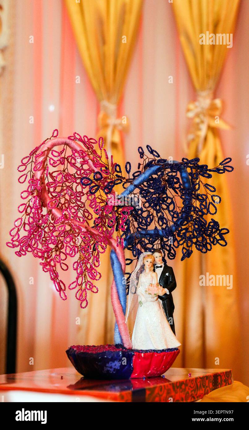 Le statuette della sposa e dello sposo si trovano sotto di essa. L'illuminazione calda e festosa migliora la scena. Ideale per matrimoni, celebrazioni o feste Foto Stock