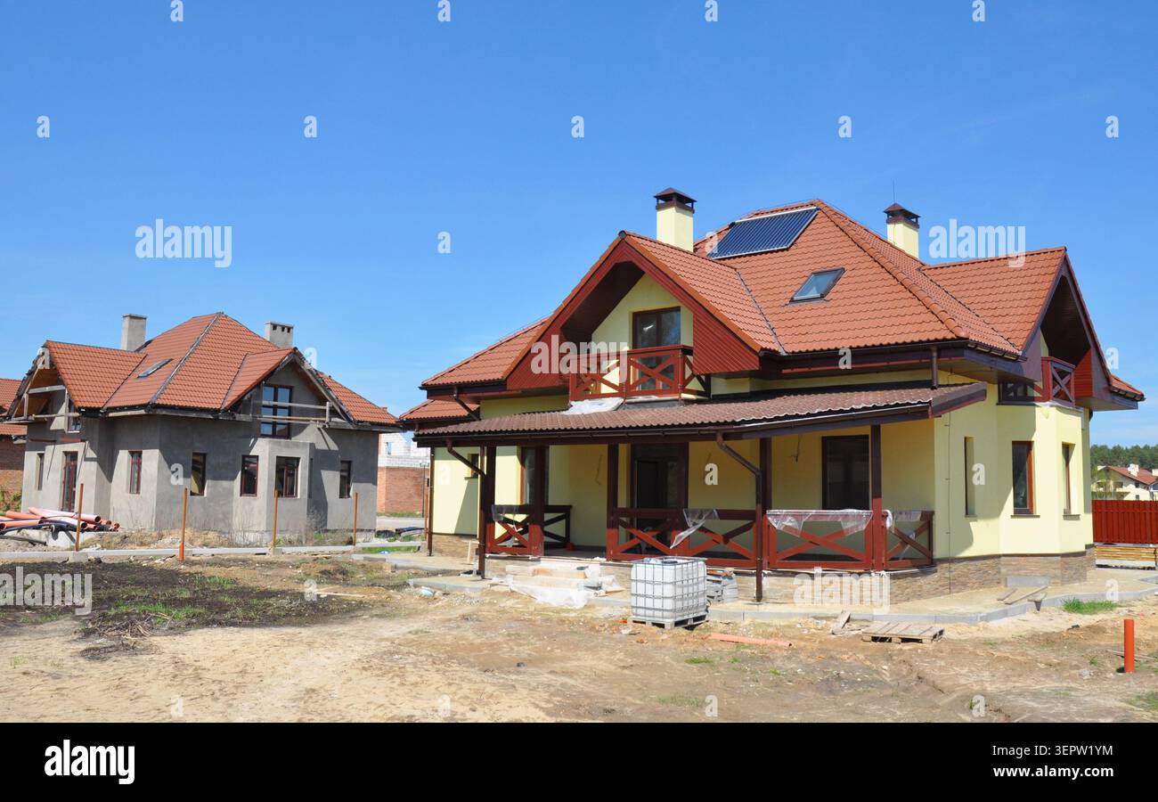 Casa in costruzione. Cantiere edile con tetto in argilla, fulmine, pannelli scaldabagno solari, lucernari nell'attico, illuminazione del tetto professionale Foto Stock
