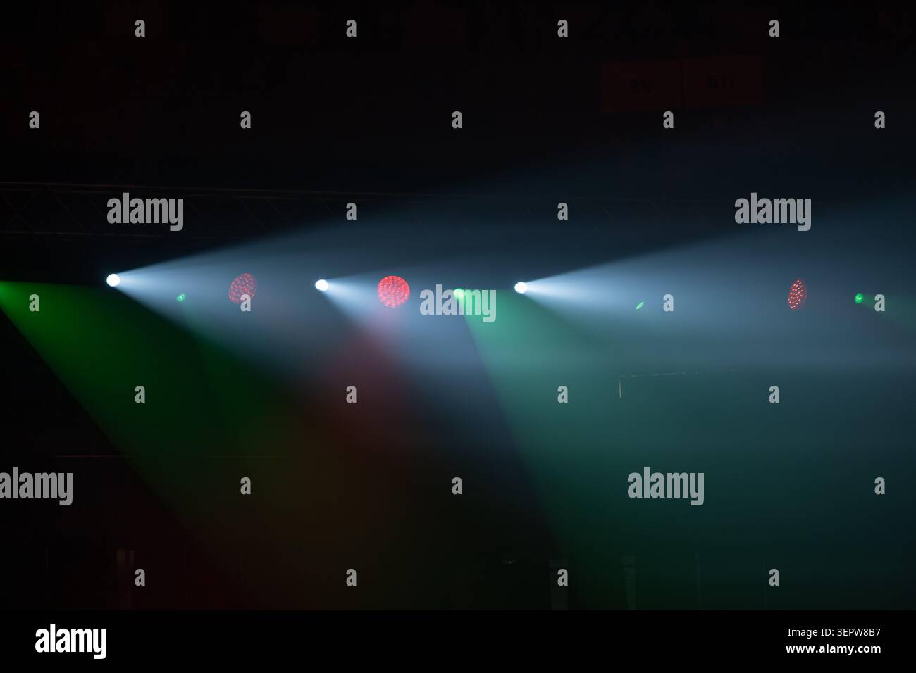 I riflettori del palcoscenico perforano l'aria fumosa, fasci colorati che si estendono su palcoscenici vuoti, concerti drammatici e illuminazione del teatro. Foto Stock
