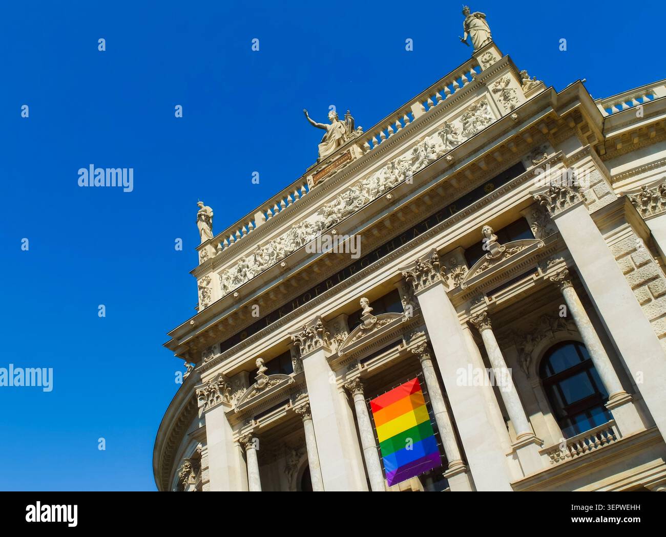 La bandiera arcobaleno appesa a un edificio teatrale a Vienna, Austria, simboleggia il sostegno municipale alla comunità LGBTQ Plus. Foto Stock