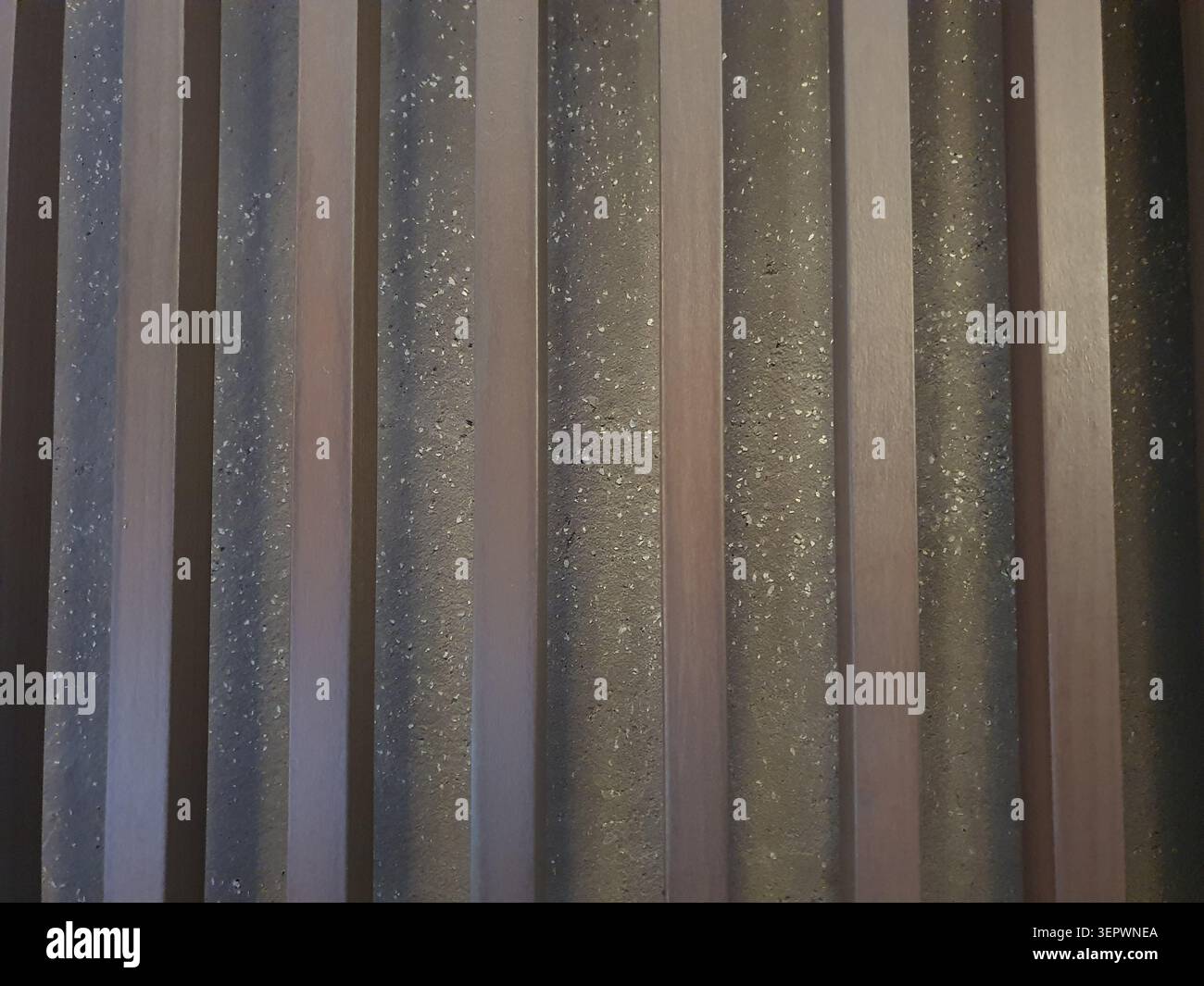 Foto telefonica di barre di legno posizionate contro un muro di pietra. Dettagli architettonici rustici che mostrano texture, materiali naturali e contrasto strutturale. Foto Stock
