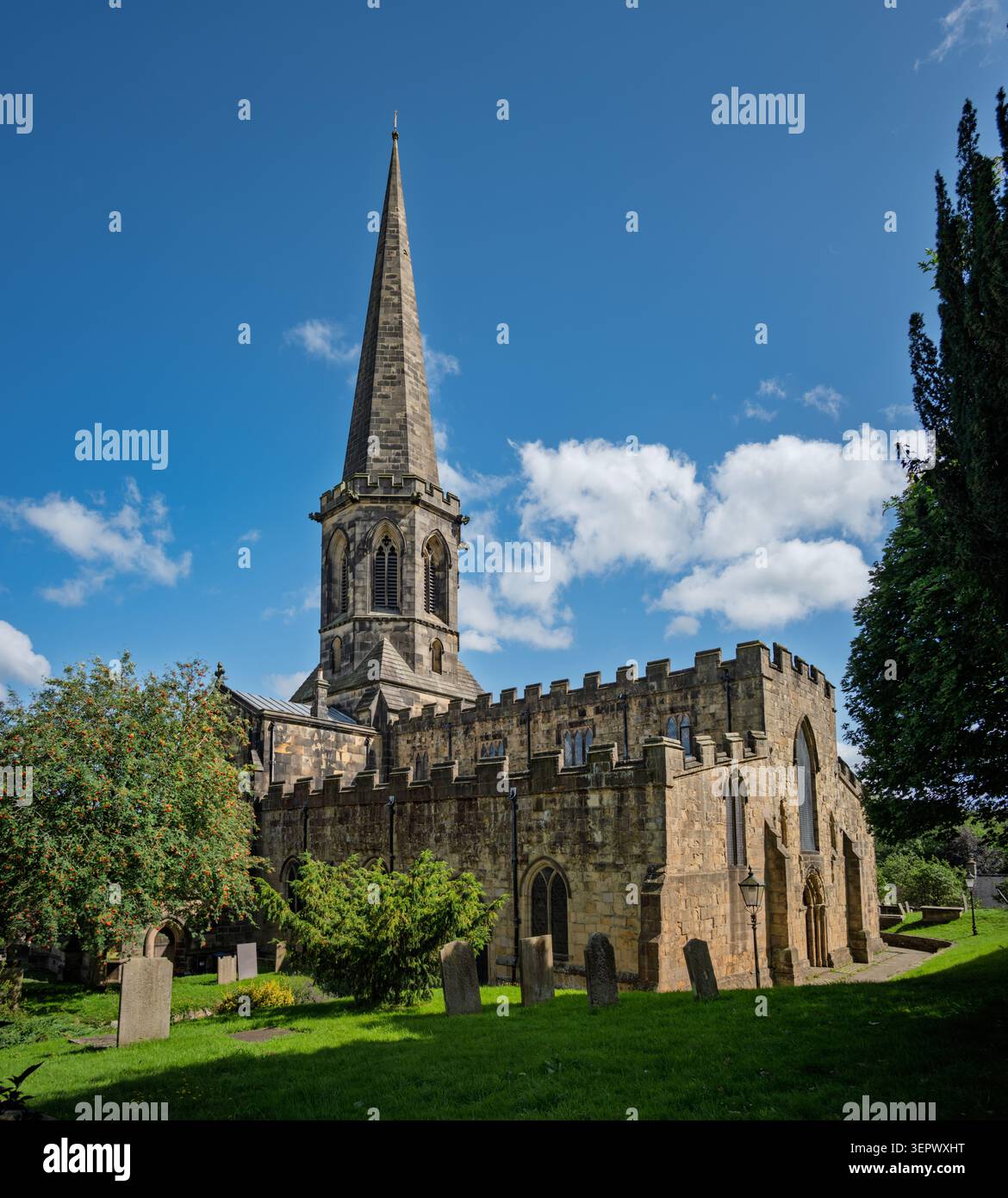 Vista panoramica esterna della Chiesa di tutti i Santi, con la sua iconica guglia ottagonale e il cimitero a Bakewell, Peak District Foto Stock