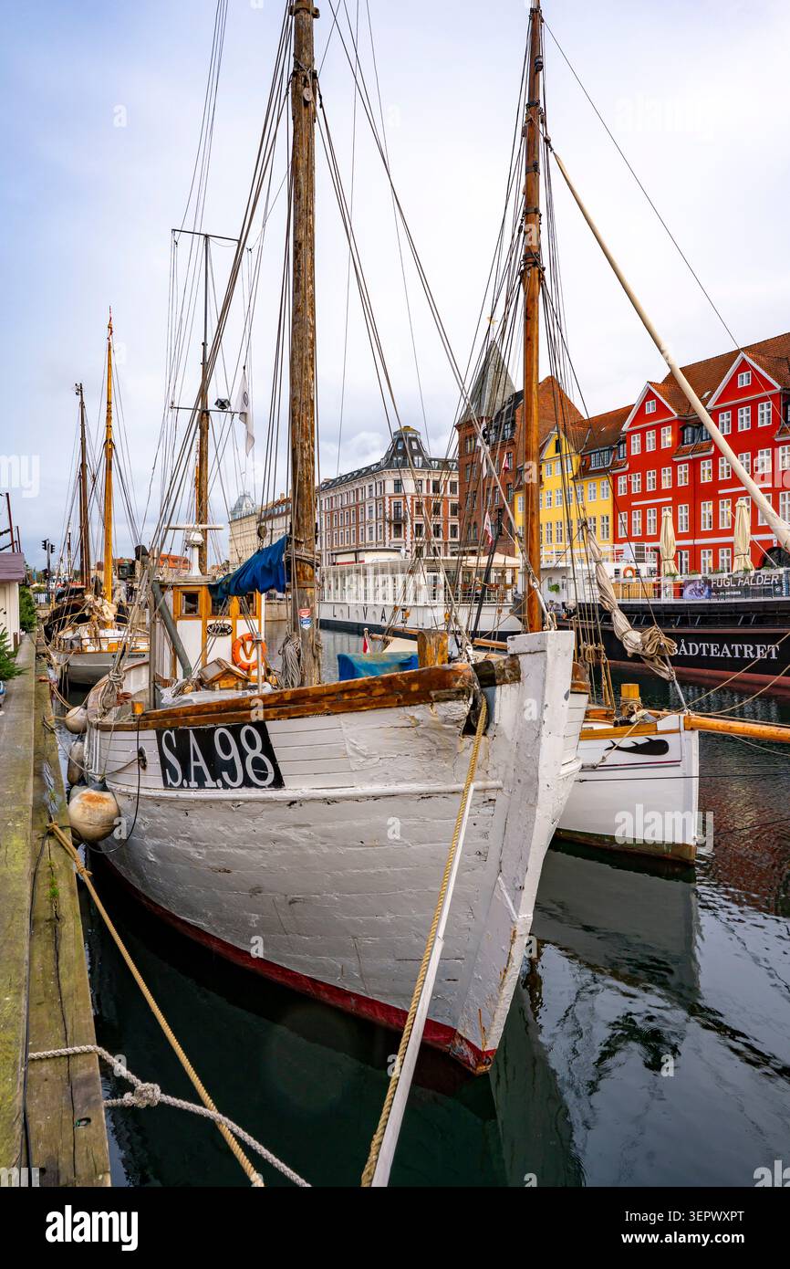 Tradizionali barche a vela in legno nello storico porto di Nyhavn a Copenaghen, Danimarca, fiancheggiate da case cittadine dai colori vivaci del XVII secolo Foto Stock