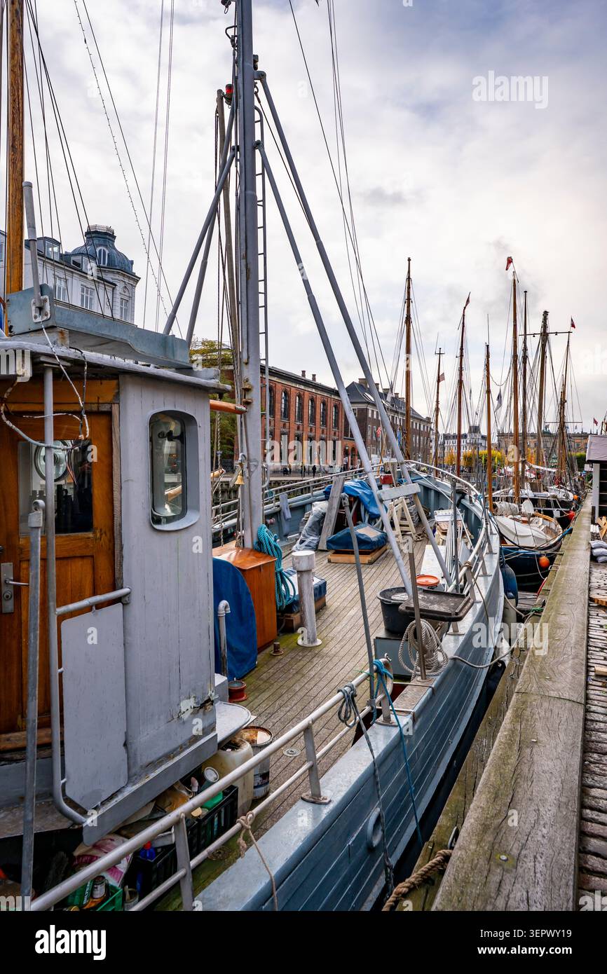 Tradizionali barche a vela in legno nello storico porto di Nyhavn a Copenaghen, Danimarca, fiancheggiate da case cittadine dai colori vivaci del XVII secolo Foto Stock