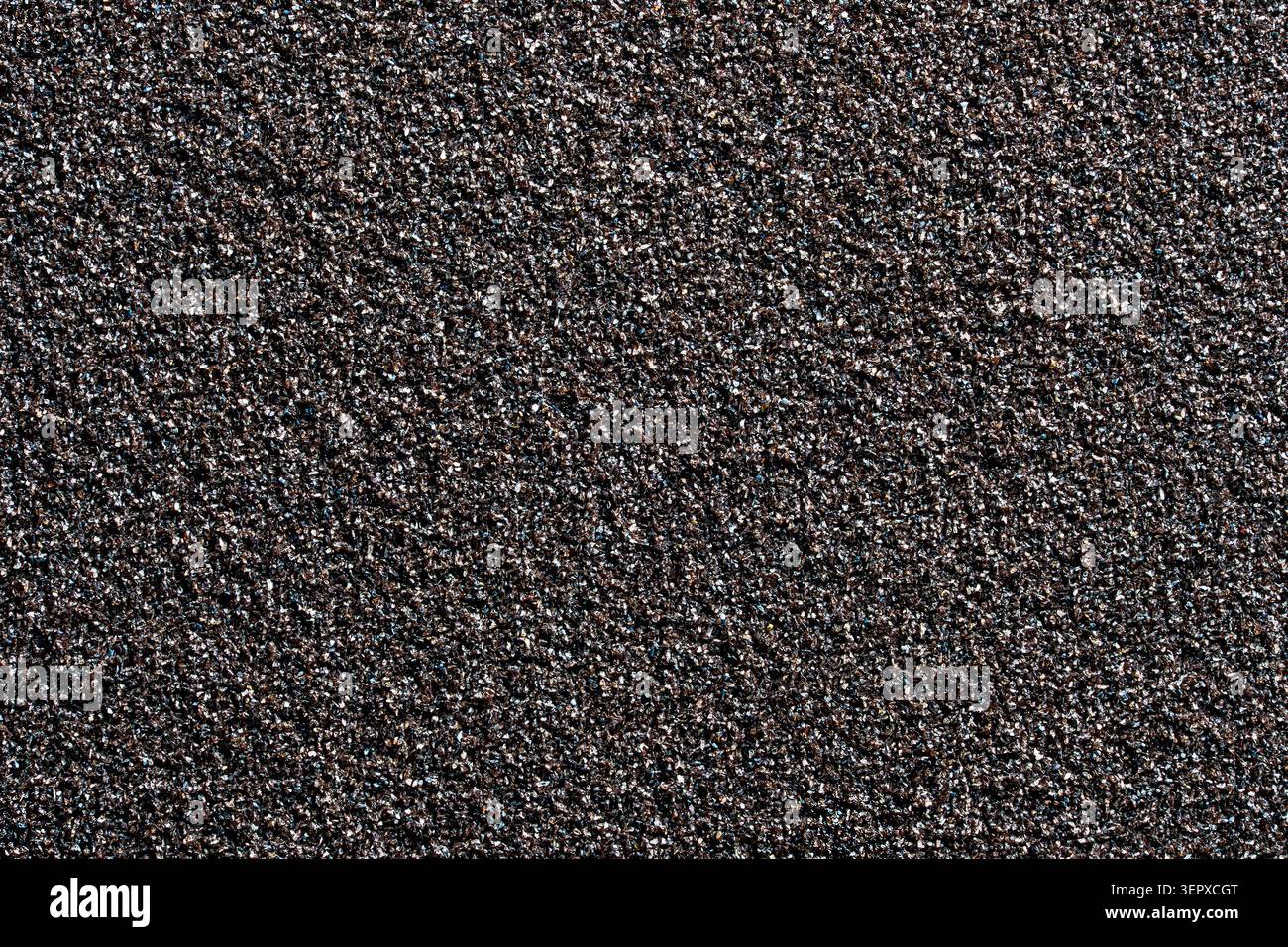 Una foto macro full-frame ad alta risoluzione di una texture abrasiva scura, grossa e granulosa, simile alla carta vetrata o a una superficie in pietra ruvida. Ideale per Foto Stock