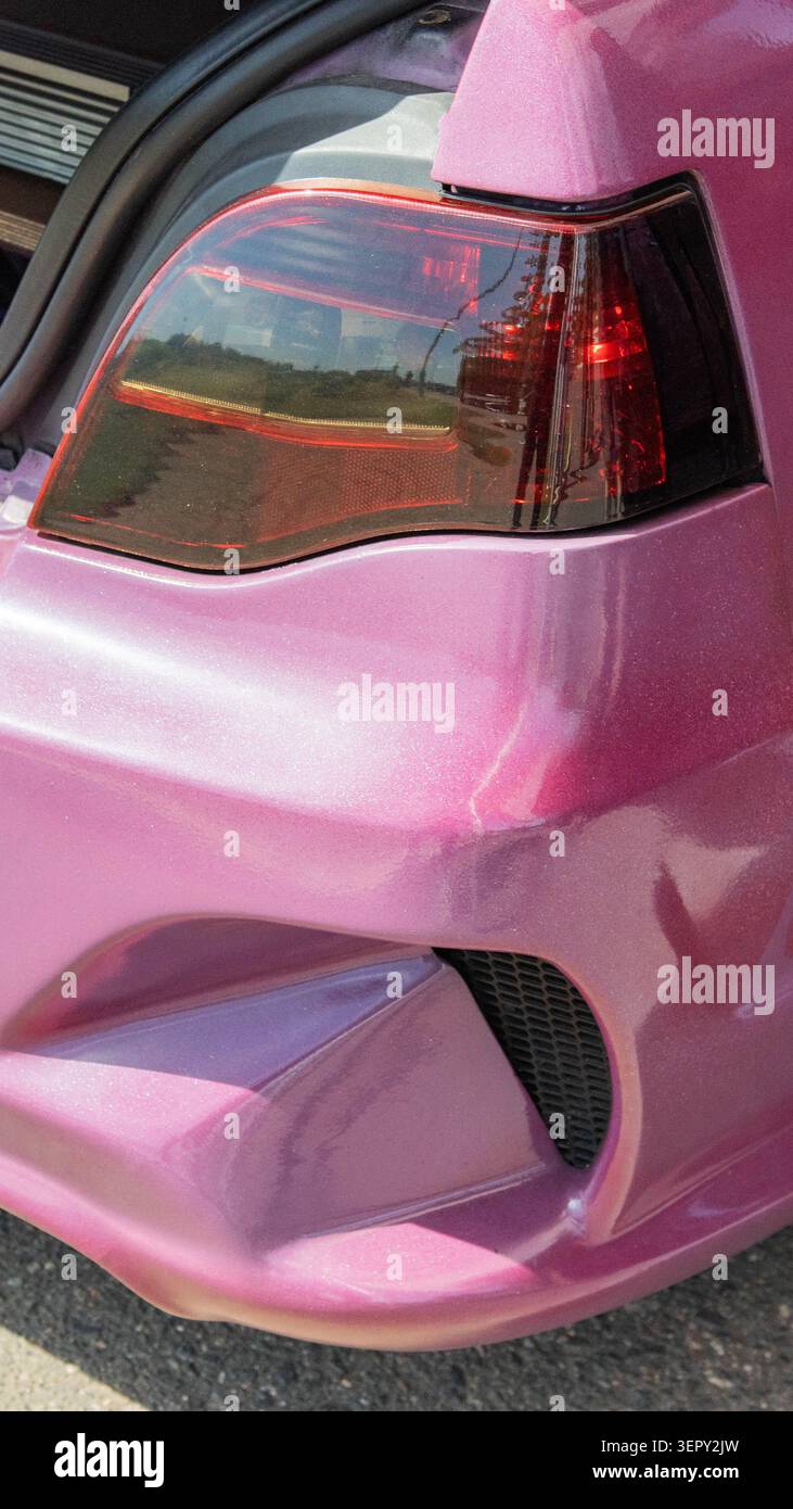 Vista ravvicinata della verniciatura personalizzata rosa glitter del paraurti posteriore e delle luci posteriori, che enfatizza la finitura lucida e i dettagli complessi della carrozzeria. Visualizzazione di Foto Stock
