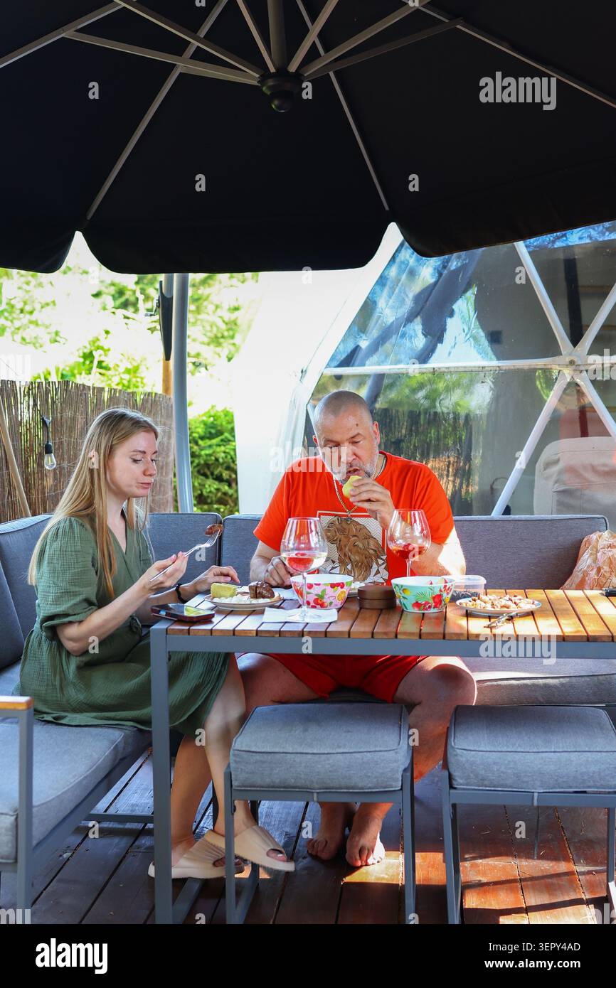 Rifugio romantico per il fine settimana con vino, cibo e conversazione in un ambiente glamping di prima qualità sotto il sole estivo. Foto Stock