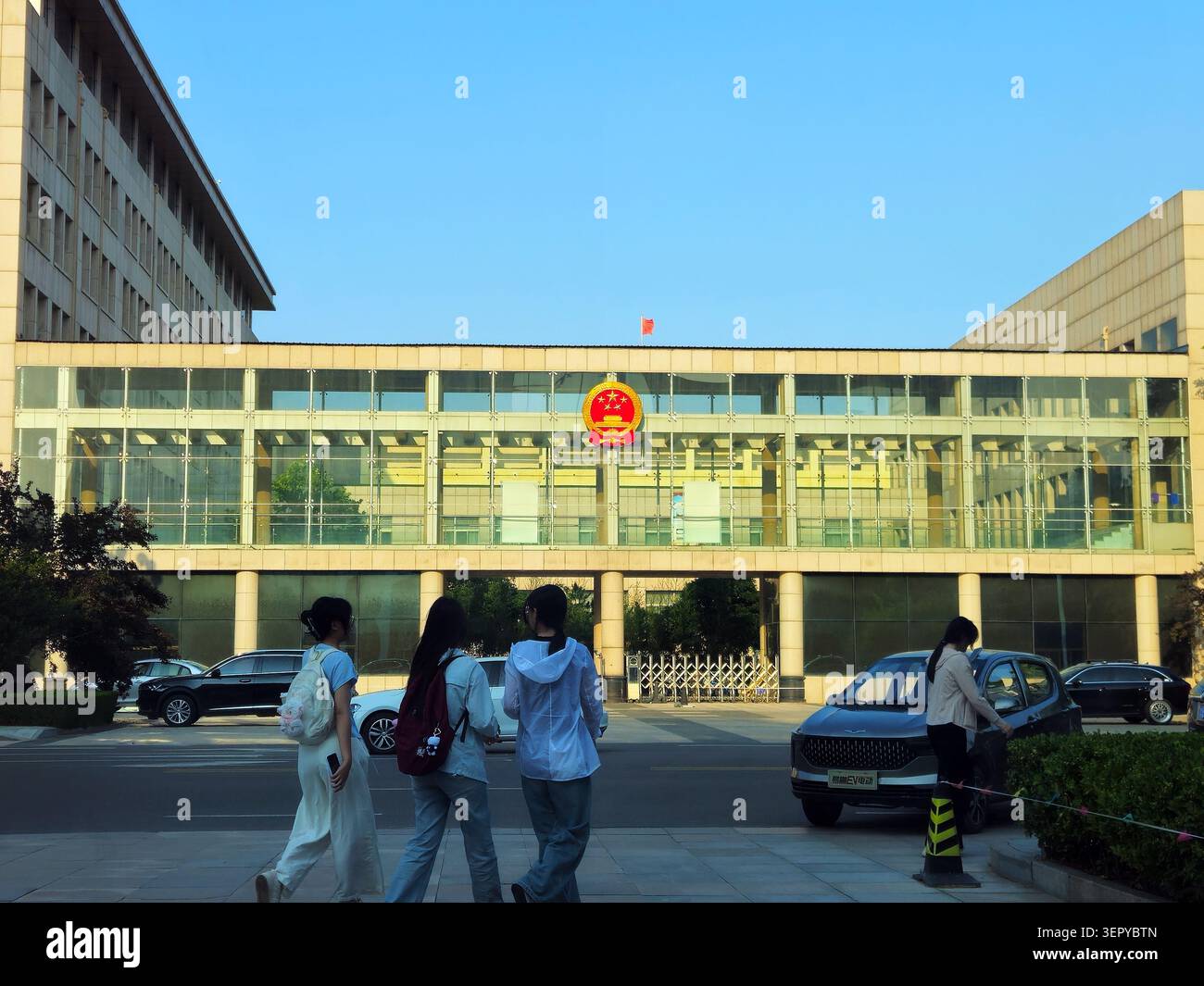 I giovani pedoni passano davanti a un edificio degli uffici governativi cinesi Foto Stock