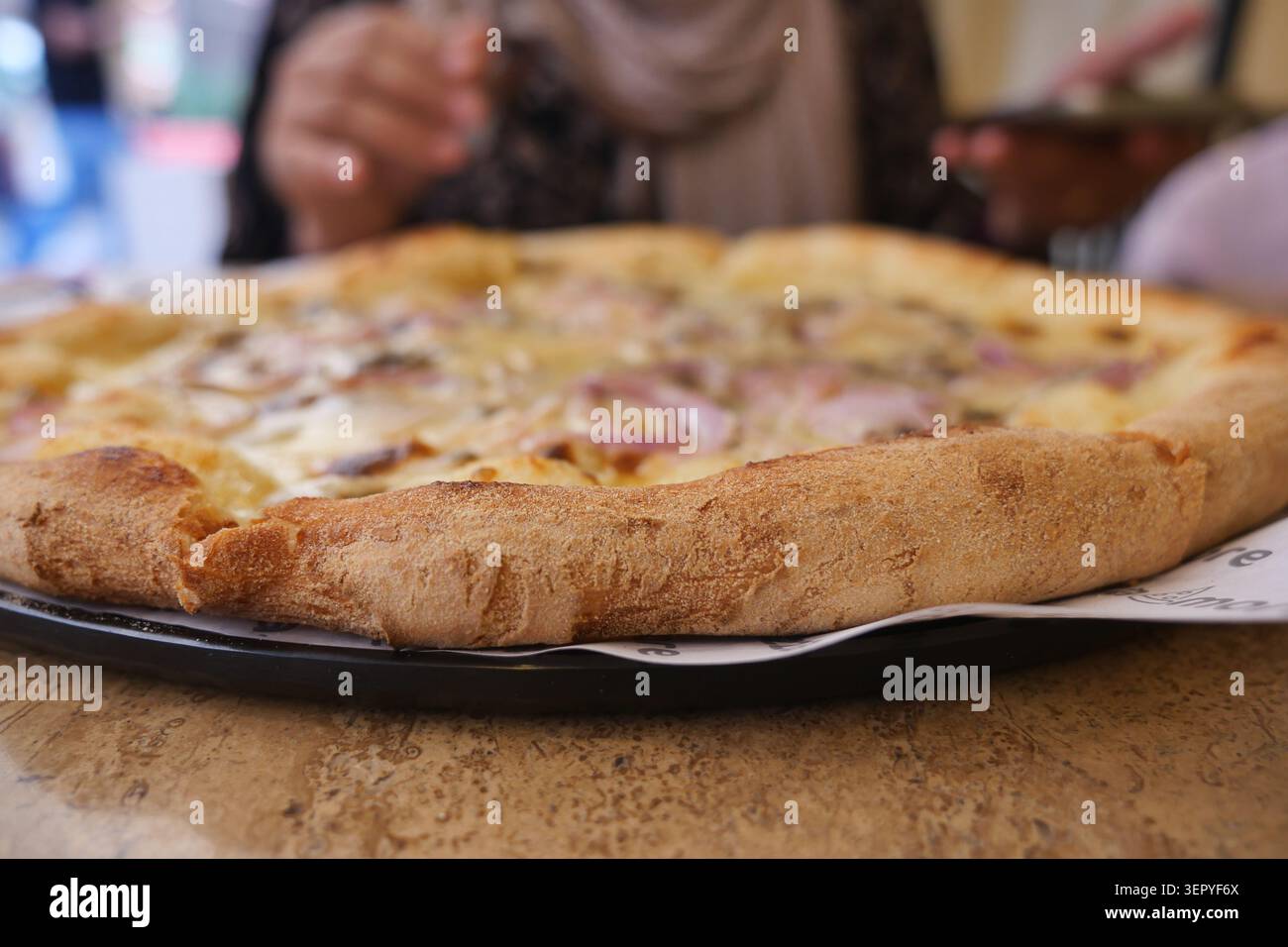 Pizza appena sfornata su un tavolo in un ristorante locale Foto Stock
