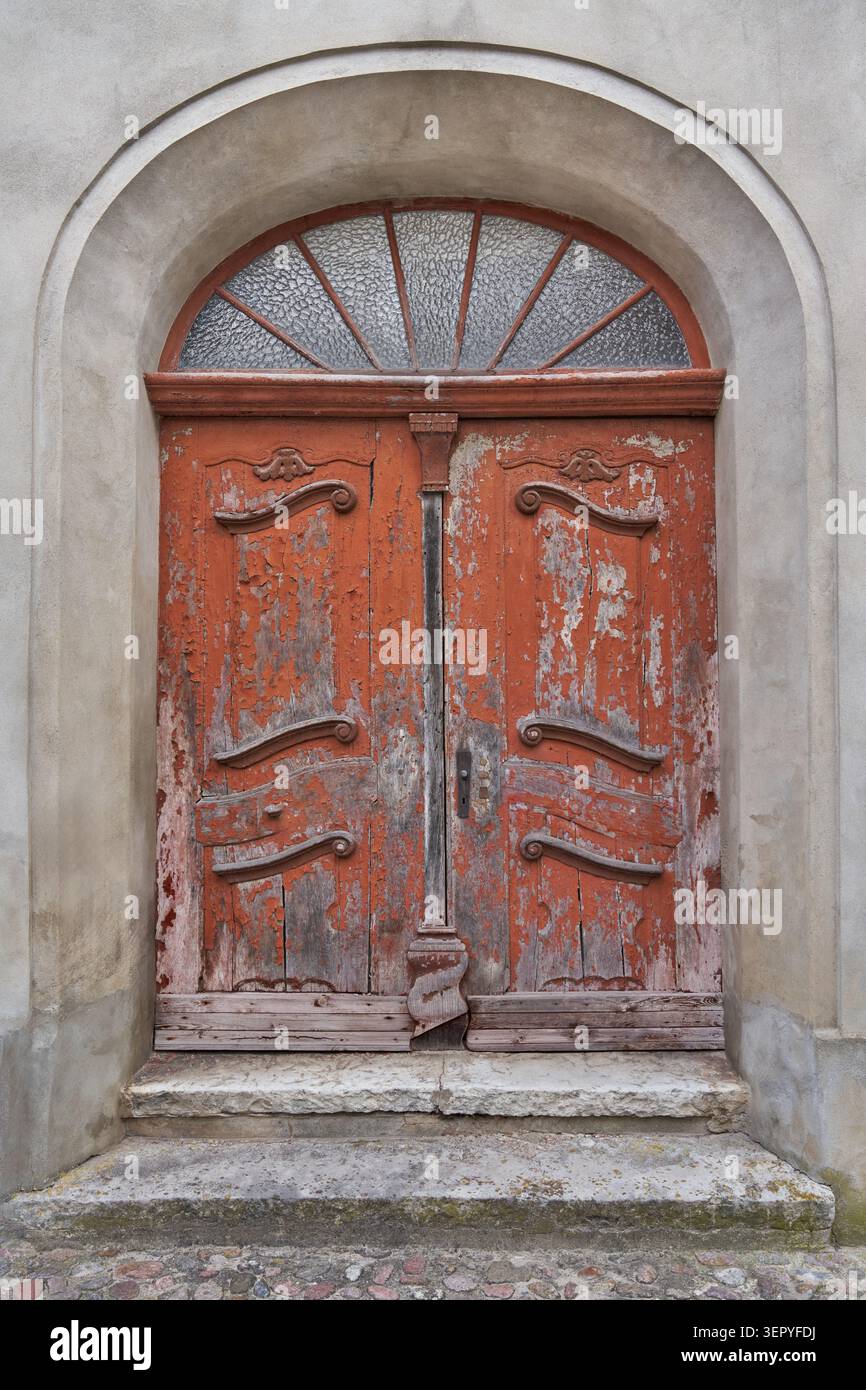 Vecchia porta in legno con finestra sullo specchio di poppa in un portale semicircolare in pietra Foto Stock