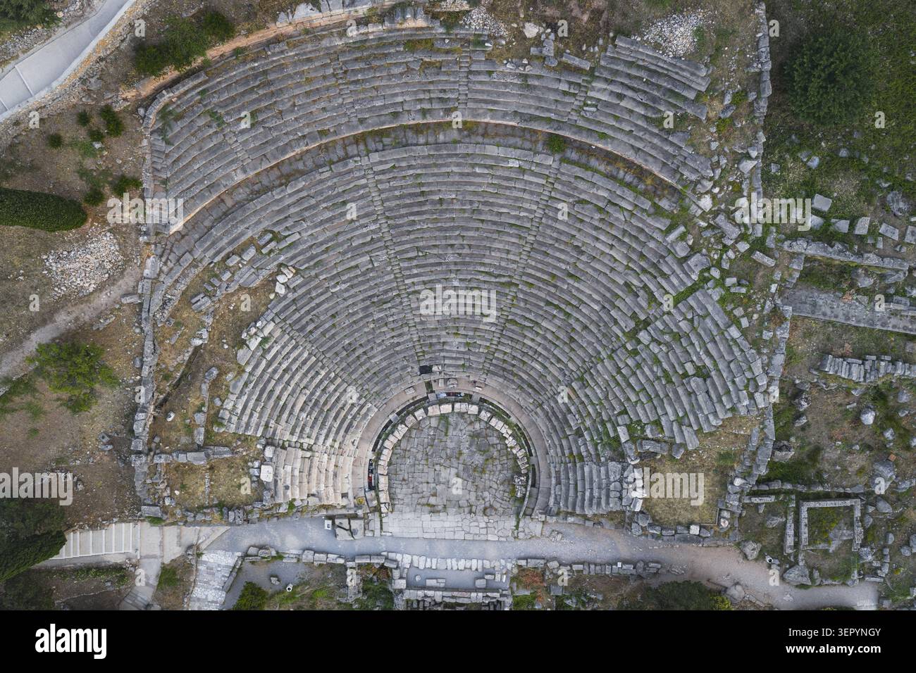 Vista aerea dell'antico teatro con posti a sedere in pietra semicircolare e rovine archeologiche sulla collina di Delfi, Grecia. Foto Stock