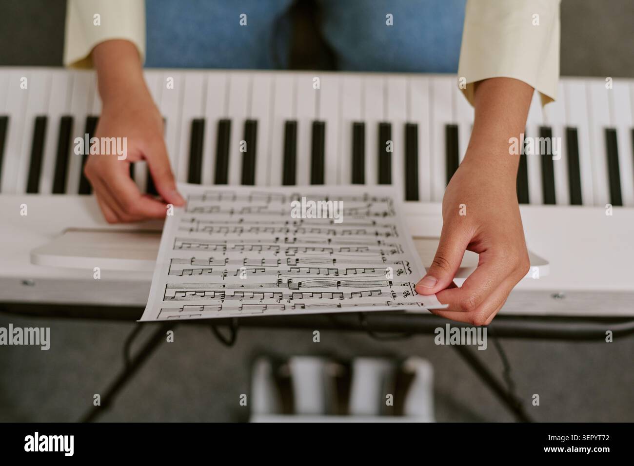 Adolescente irriconoscibile che organizza spartiti musicali su piano digitale per esercitarsi Foto Stock
