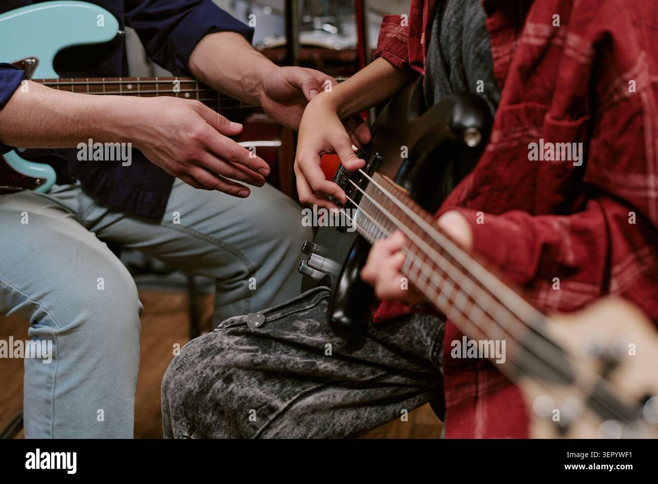 Insegnante adulto che guida adolescente che suona la chitarra basso in lezione di musica Foto Stock