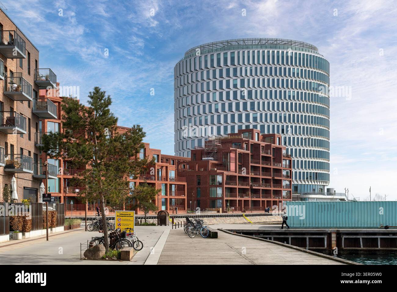 Copenaghen, Danimarca - 13 aprile 2026; passeggiata con edifici residenziali e alla fine facciata cilindrica dell'edificio per uffici sulla punta del Nord Foto Stock