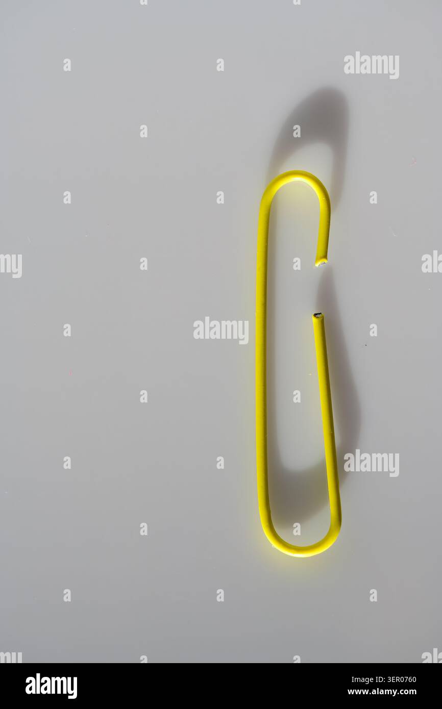 Graffetta gialla isolata su uno sfondo pulito, un concetto minimalista di cancelleria per ufficio per l'organizzazione, l'allegato e la semplicità Foto Stock
