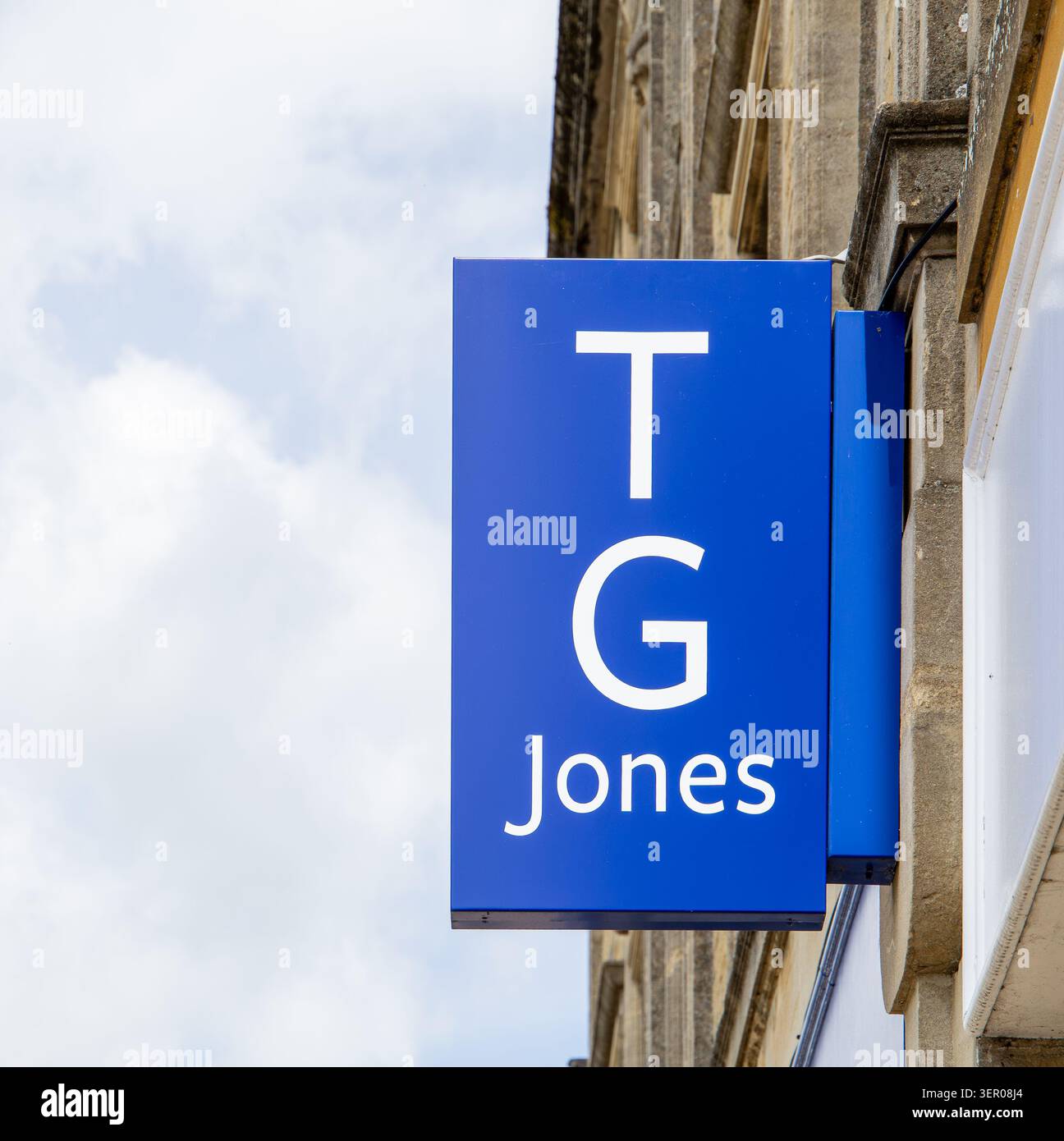 Un cartello blu che proietta il TG Jones attaccato ad una facciata in pietra di Chipping Norton Oxfordshire Foto Stock