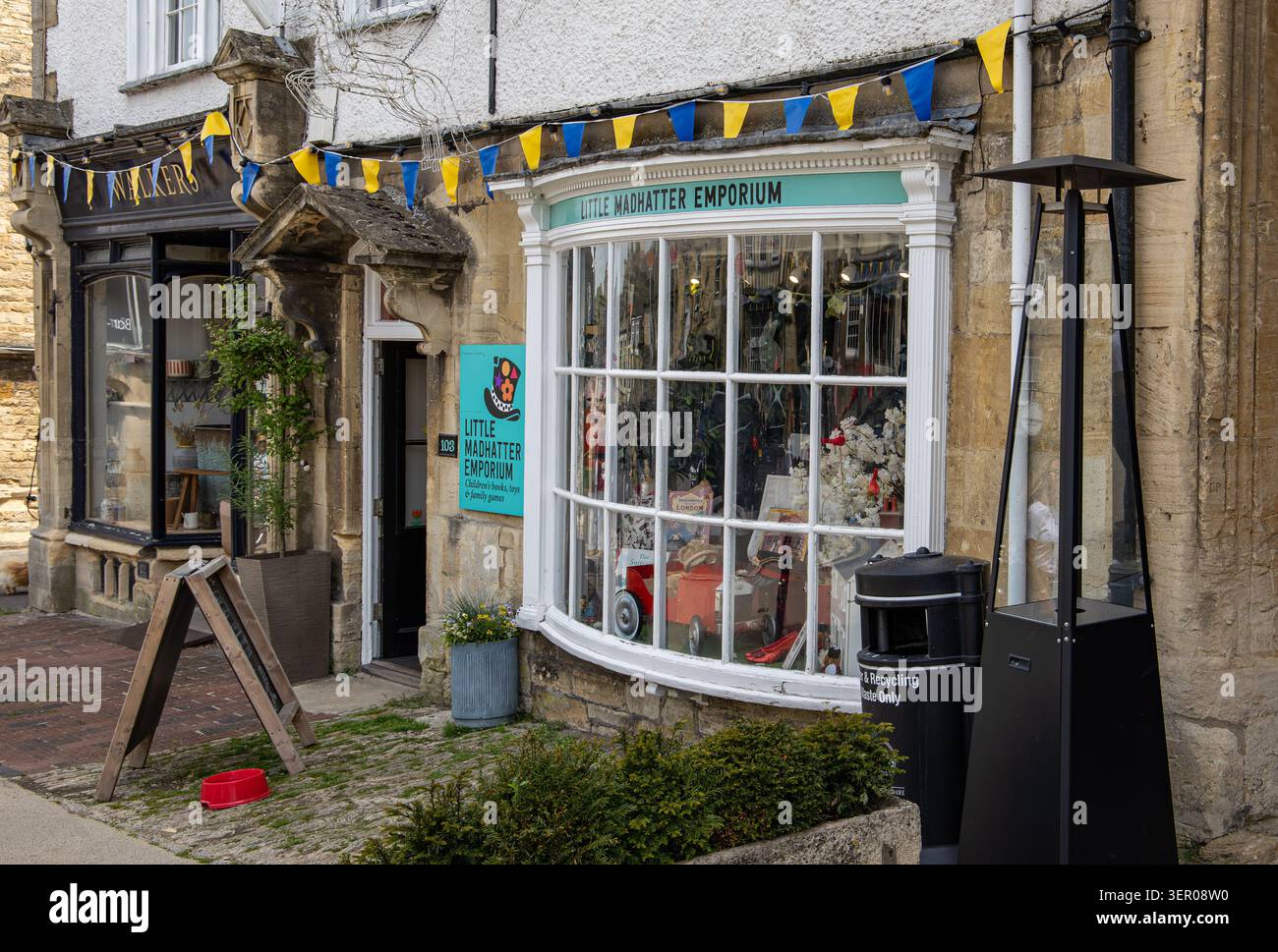 L'esterno di un affascinante negozio indipendente di giocattoli e libri chiamato Little Madhatter Emporium in uno storico edificio in pietra di Burford, Oxfordshire Foto Stock