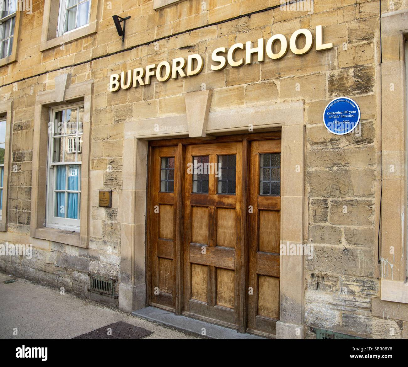 Lo storico ingresso in pietra della Burford School presenta lettere dorate e una targa blu commemorativa sul muro in muratura testurizzata Foto Stock