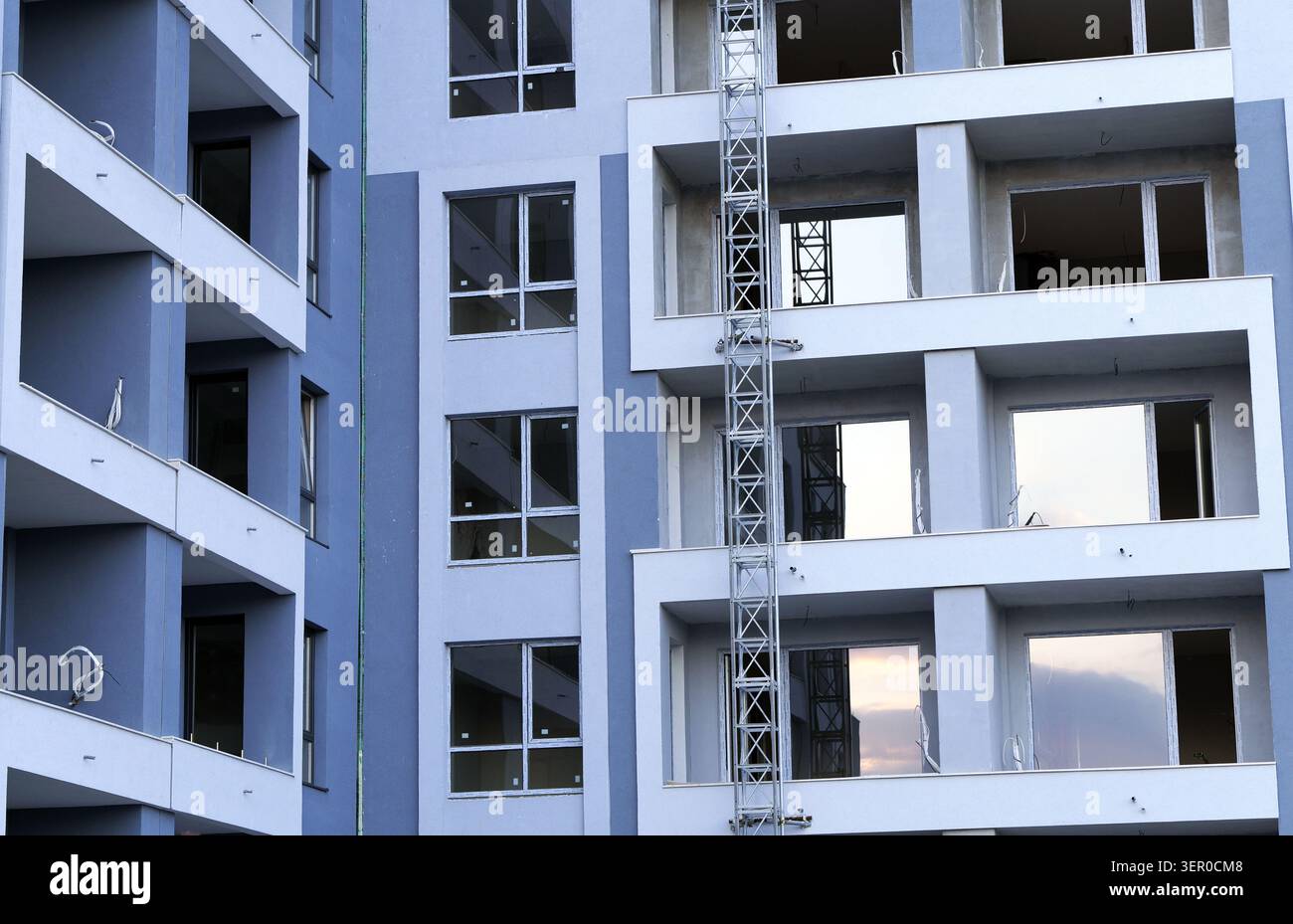 Nuova facciata del complesso di appartamenti con balconi e finestre durante la sua fase di costruzione, con impalcature su un lato, che rappresentano lo sviluppo urbano Foto Stock