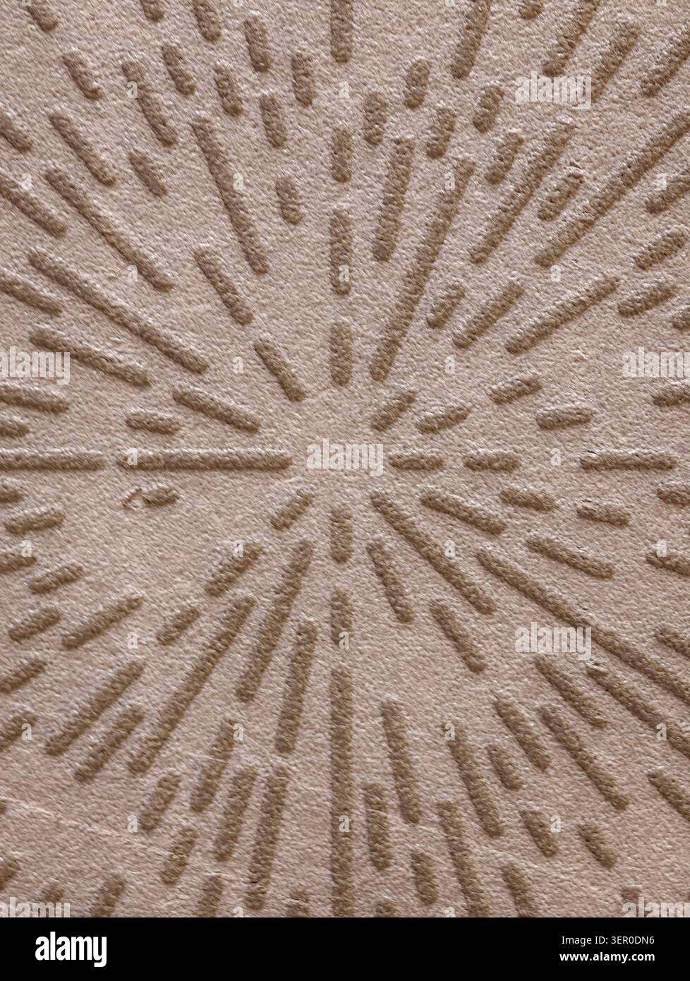 Primo piano di una superficie beige con motivo a stella goffrato con creste lineari rialzate e trattini corti che si irradiano da un punto centrale Foto Stock