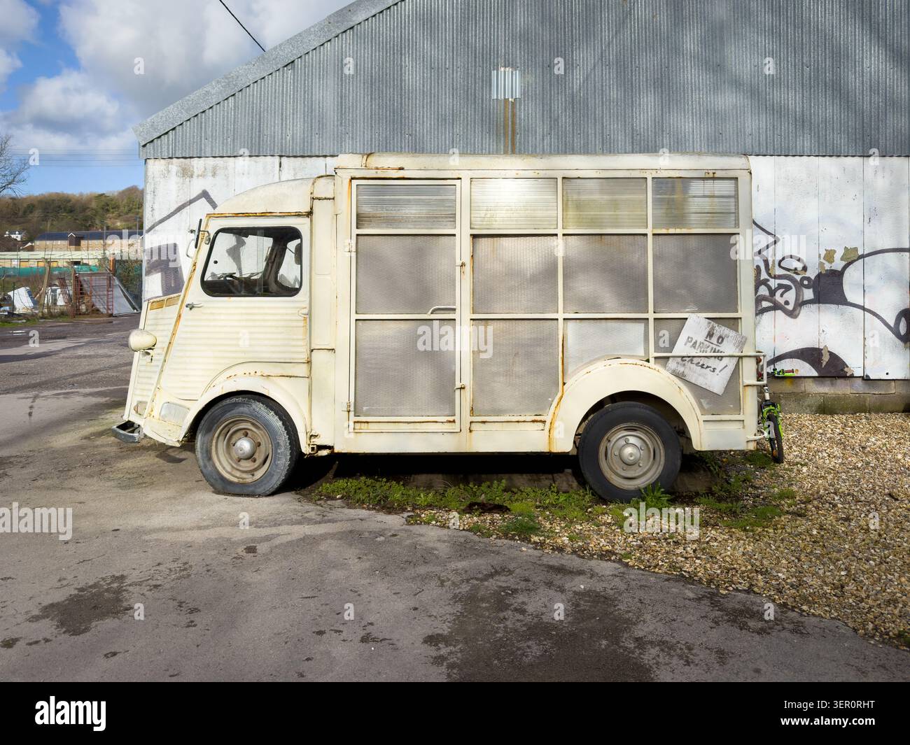 La Citroen H Van ha parcheggiato all'esterno di un edificio in metallo ondulato con graffiti e una gomma sgonfia - Immagine stock catturata con smartphone