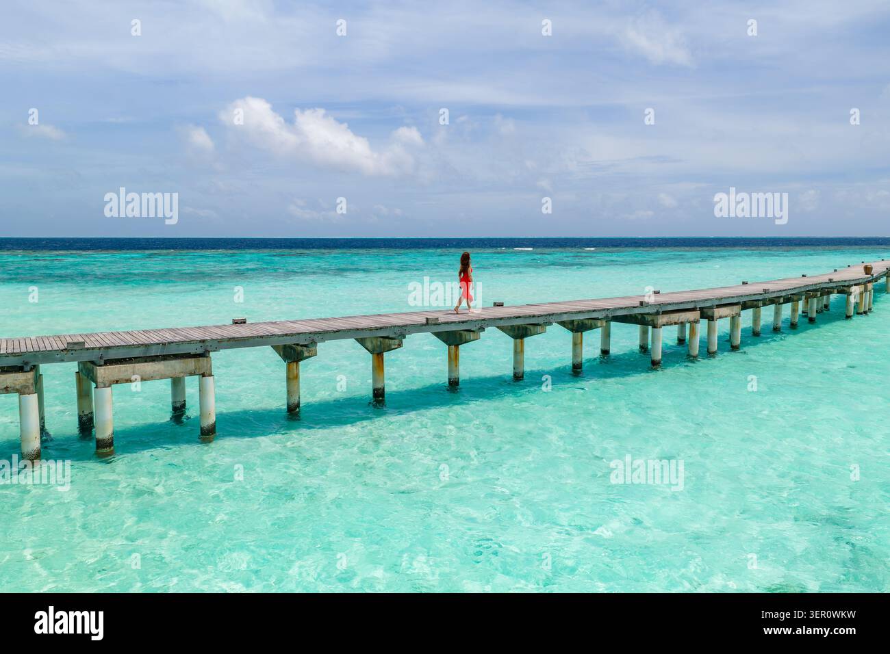 Il molo in legno delle Maldive si estende su fondali turchesi a mezzogiorno Foto Stock