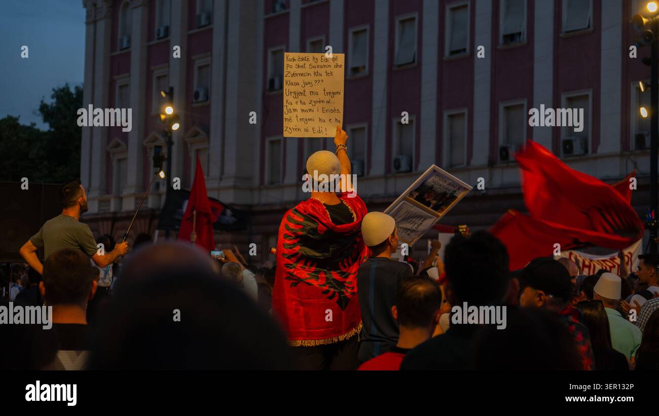 Tirana, Albania – 17 giugno 2026: I manifestanti tengono cartelli politici e bandiere albanesi fuori da un edificio governativo durante una protesta serale. Foto Stock
