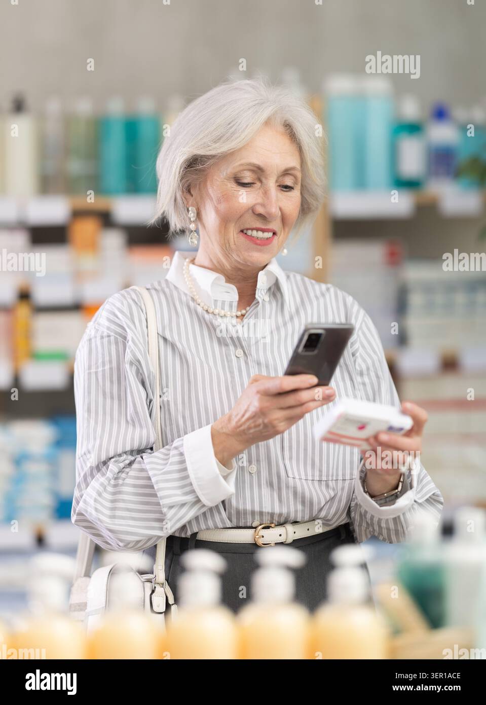 Donna anziana in abiti estivi scansiona il codice sulla confezione di pillole di paracetamolo per controllare la data di scadenza Foto Stock