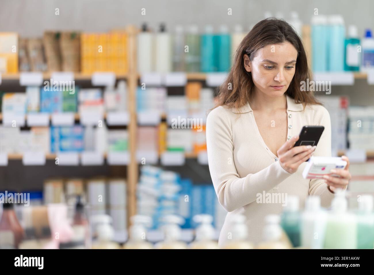 Donna in abiti estivi scansiona il codice sulla confezione di pillole di paracetamolo per controllare la data di scadenza Foto Stock