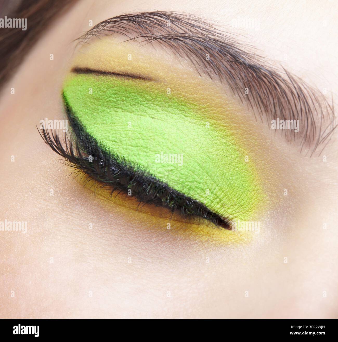 Foto macro di primo piano di un occhio umano femminile chiuso. Donna con un trucco di bellezza per il viso di moda. Ragazza con pelle perfetta e ombre verdi e gialle agli occhi Foto Stock